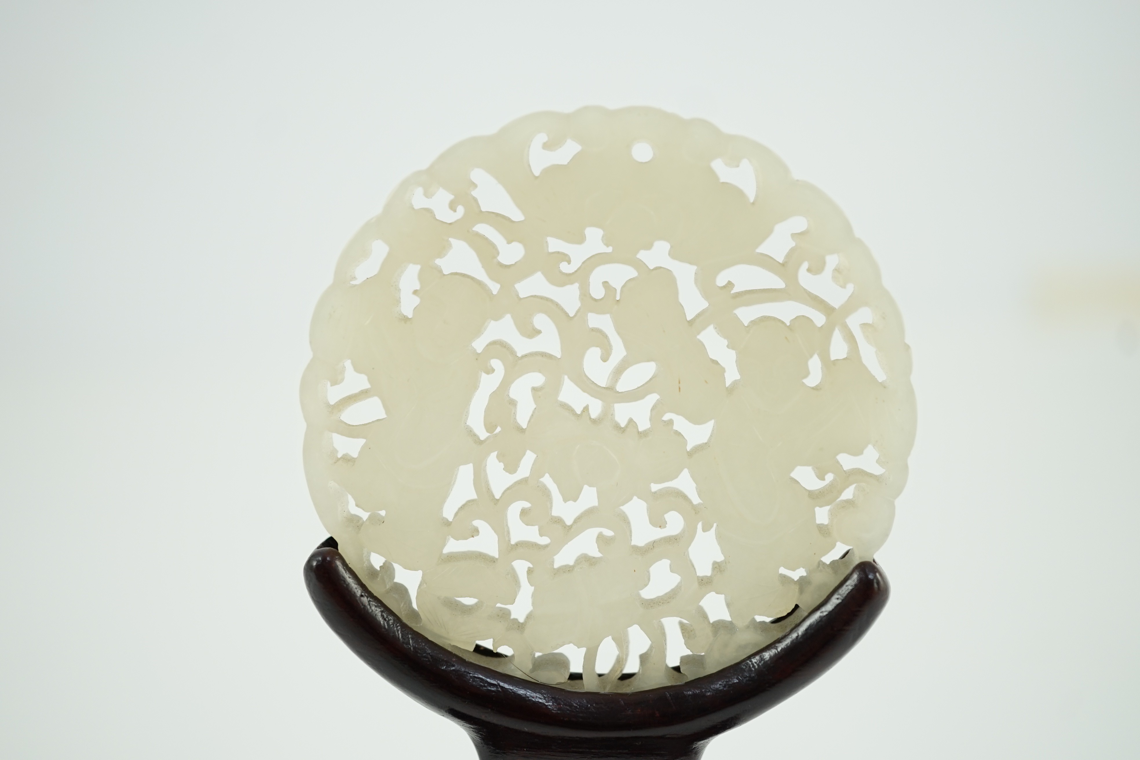 A Chinese white jade ‘Hehe Erxian’ disc, 19th/20th century, 5.6cm diameter, wood stand